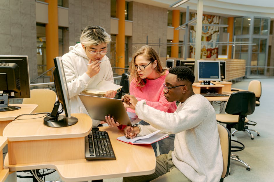 A group of students working on a laptop together in a modern library setting.